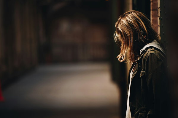 Sad female teenager in a dark hallway